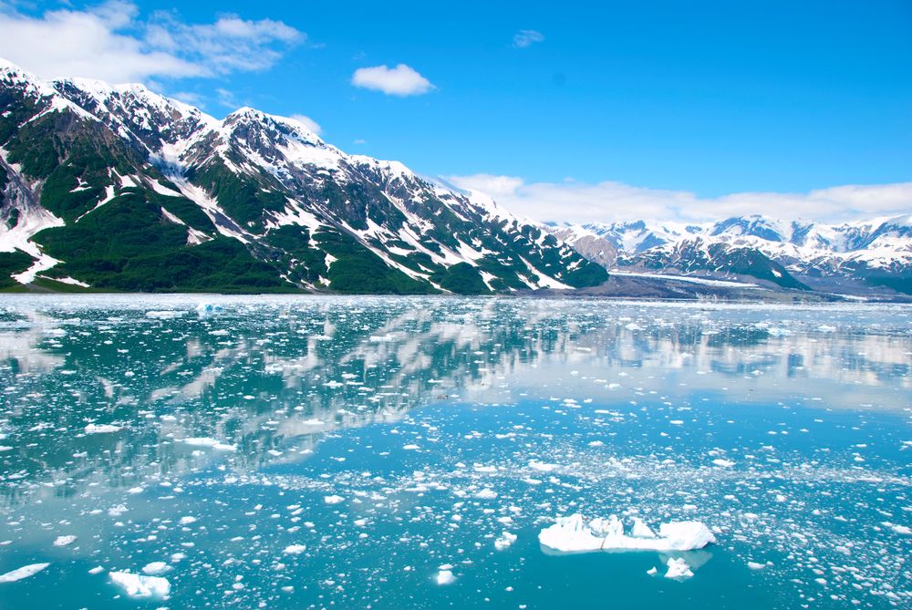 Snow-covered mountains rising above calm water on the Alaska coast